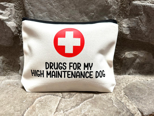 canvas pouch with red cross and text 'Drugs for my high maintenance dog' on stone surface