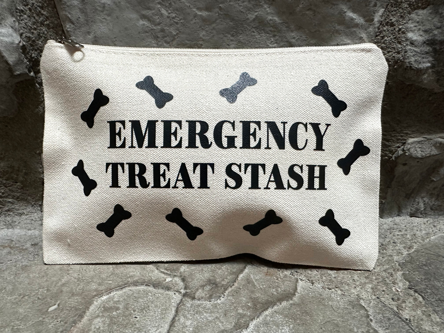 Canvas pouch with 'Emergency Treat Stash' text and bone designs on a stone surface