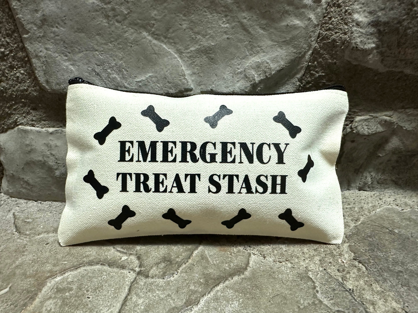 canvas pouch with 'Emergency Treat Stash' text and black bone symbols on a stone background