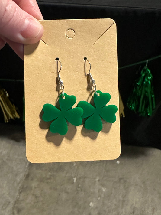 Two green acrylic shamrock earrings with stainless hooks displayed on a beige card.