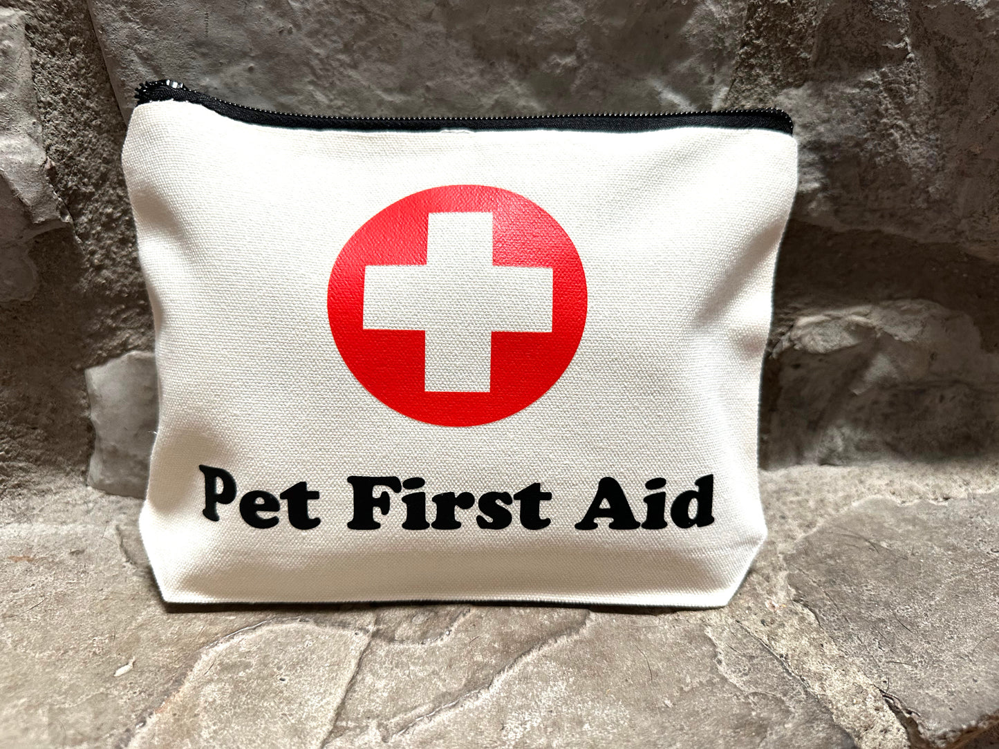 Pet first aid kit with a red cross symbol on a stone surface