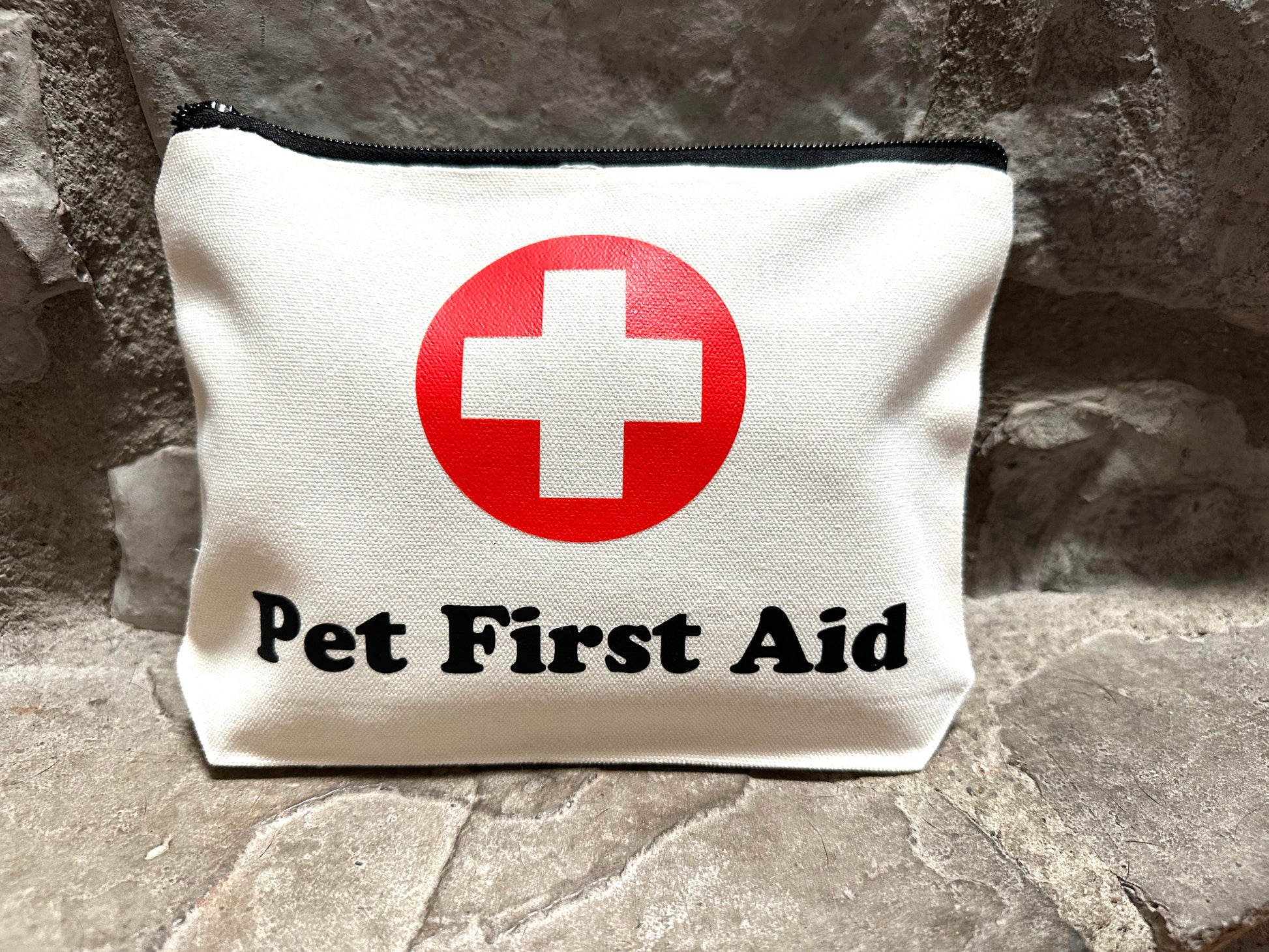 Pet first aid kit with a red cross symbol on a stone surface