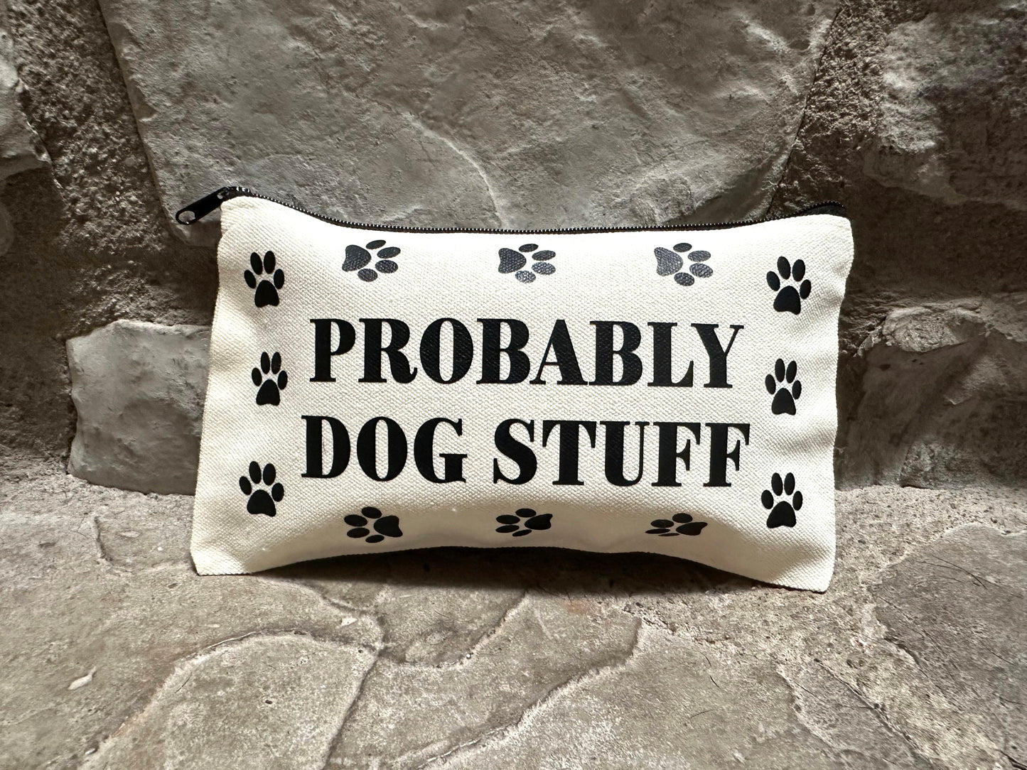 Canvas pouch with 'PROBABLY DOG STUFF' text and paw prints on a stone surface