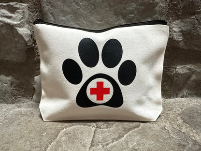 canvas pouch with black paw print and red cross on a stone surface